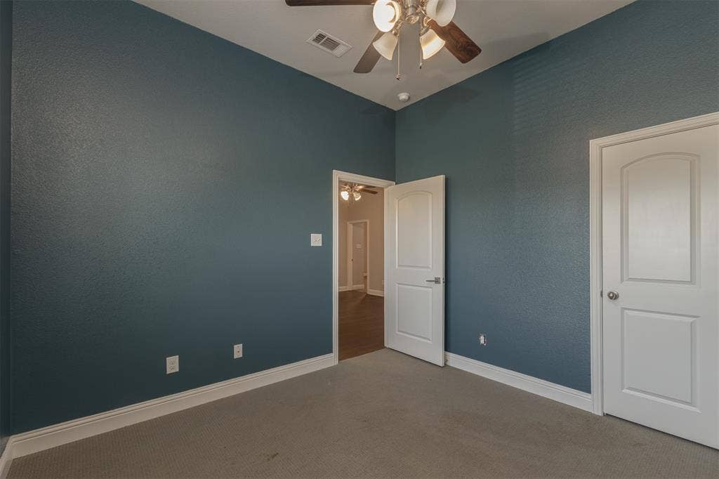 Interior room featuring high ceilings, neutral carpeting, and a ceiling fan with integrated lighting