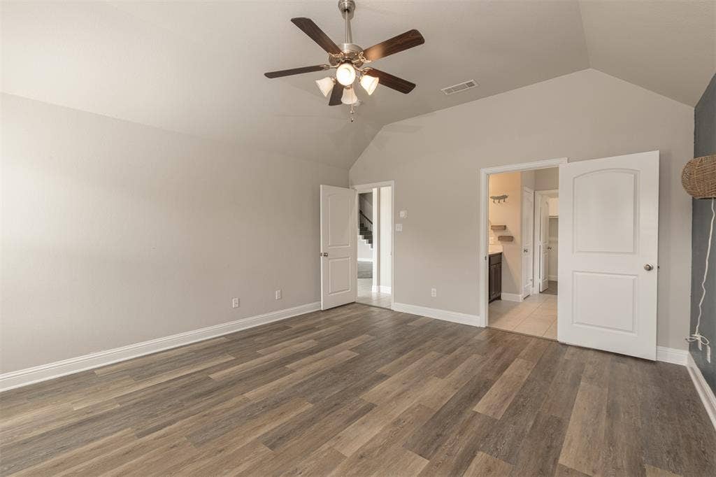 Vaulted ceilings, wood-finish flooring, and a multi-light ceiling fan with integrated illumination