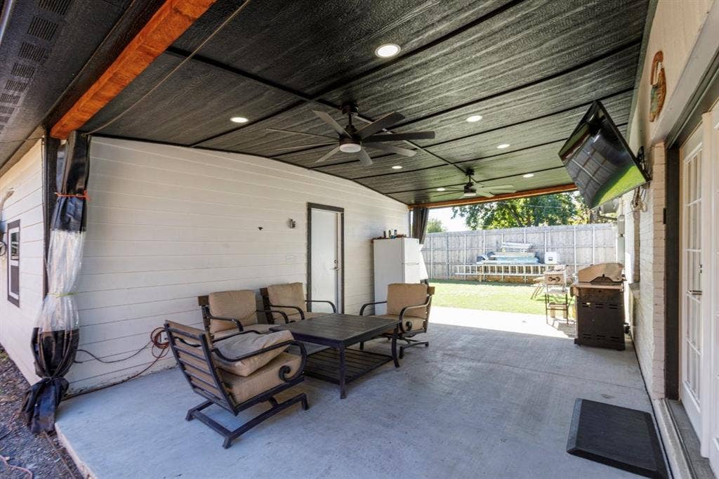 Covered patio featuring a concrete floor, recessed lighting, dual ceiling fans, and wood-paneled walls