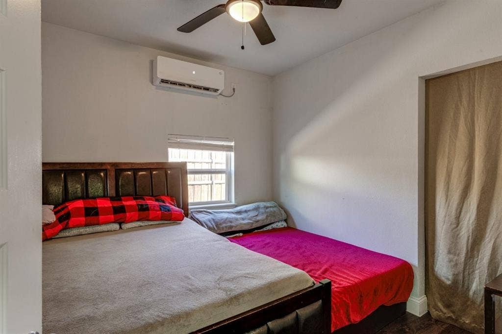 Room featuring a wall-mounted ductless mini-split HVAC unit, ceiling fan with integrated lighting, and window with blinds