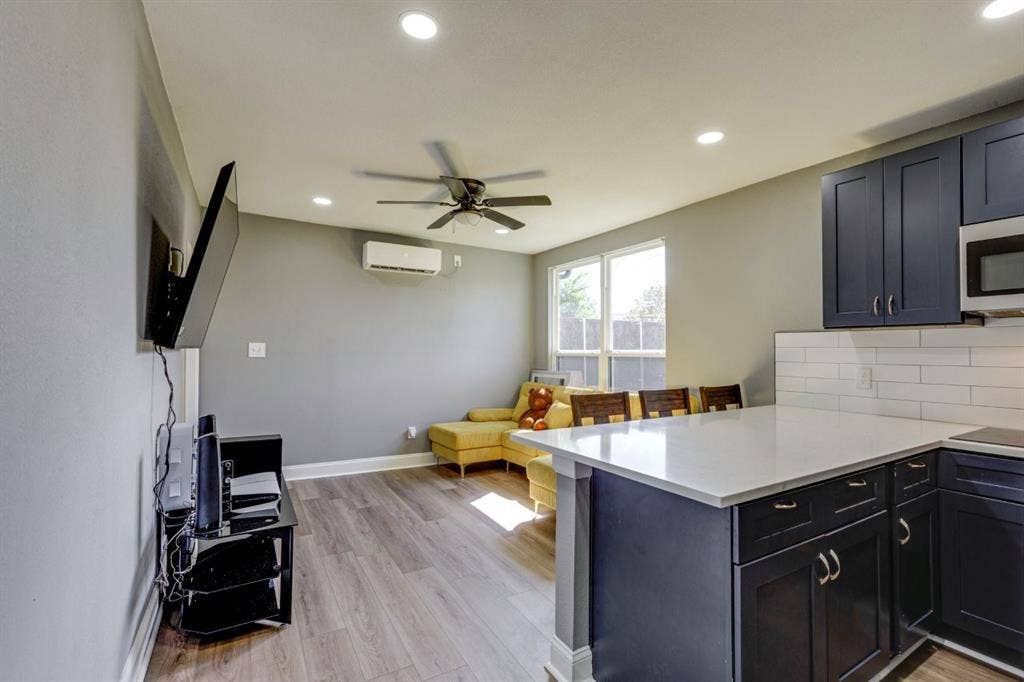 Kitchen featuring navy cabinetry, quartz countertops, white subway tile backsplash, wood-finish flooring, and recessed lighting