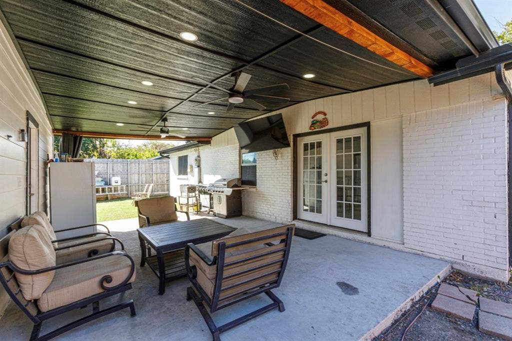 Covered patio featuring a painted wood-slat ceiling, recessed lighting, ceiling fan, and white-painted brick exterior