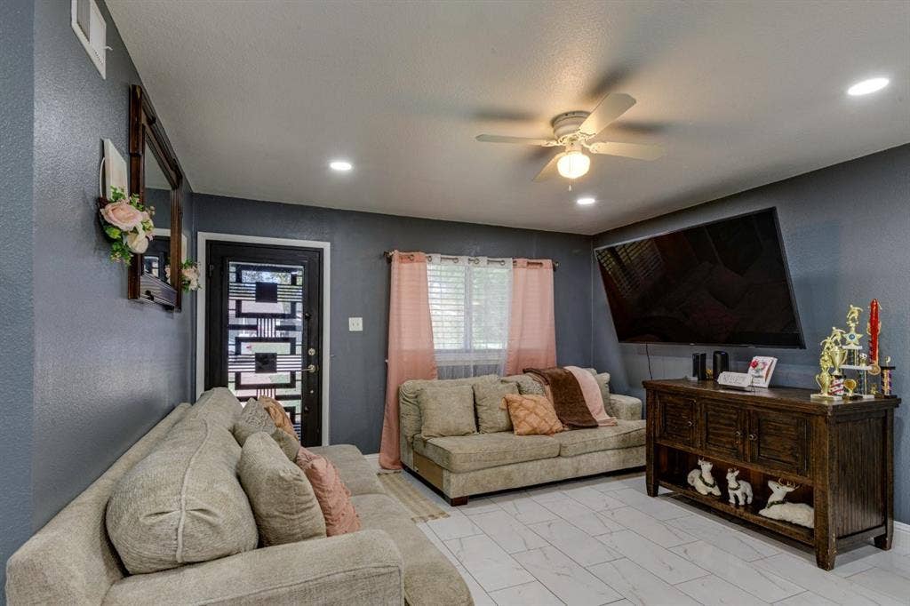 Living area featuring white tile flooring with veining, recessed lighting, a ceiling fan, and an entry door with decorative metal inset