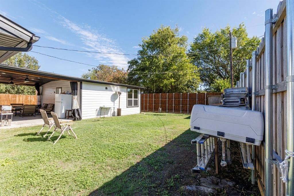 Backyard featuring a concrete patio, wood privacy fencing, and a covered outdoor area