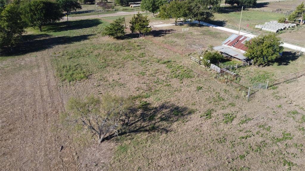 Expansive acreage featuring mature trees, perimeter fencing, and an existing structure with a metal roof