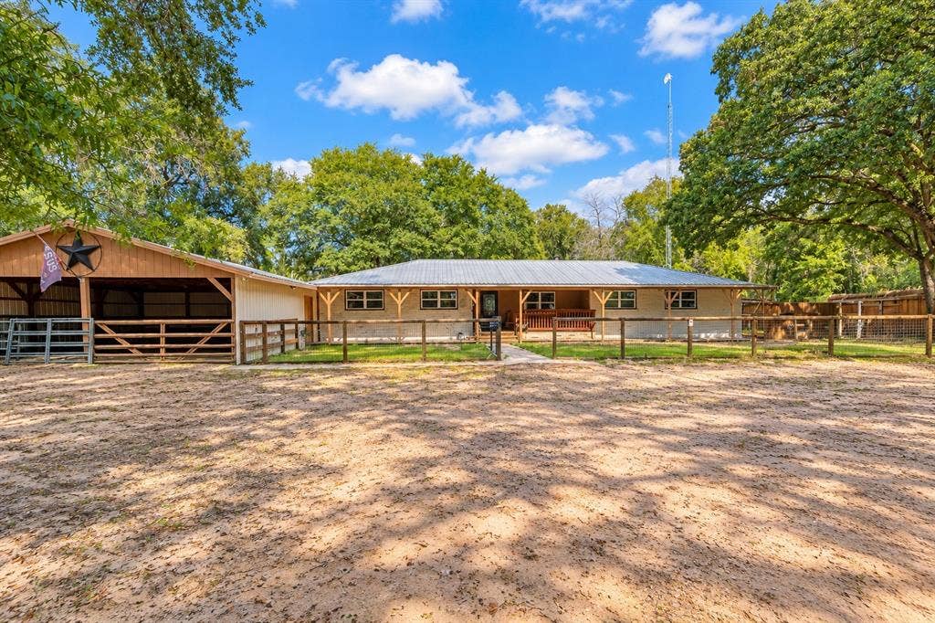 13672 County Road 2915, Eustace, TX 75124 Exterior featuring a light-toned facade, metal roof, covered front porch with wooden support beams, and attached carport with post-and-rail fencing