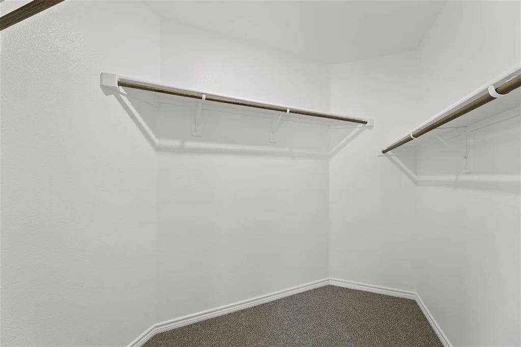 Walk-in closet featuring neutral carpeting and multi-tier wall-mounted shelving with integrated hanging rods