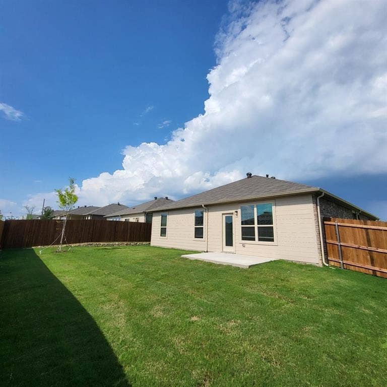 Rear exterior featuring light-toned horizontal siding, a concrete patio, and a fully enclosed wood privacy fence