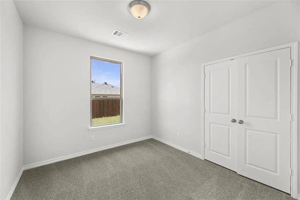 Neutral interior space featuring neutral wall paint, carpeting, a single-pane window, flush-mount ceiling lighting, and double-panel closet doors