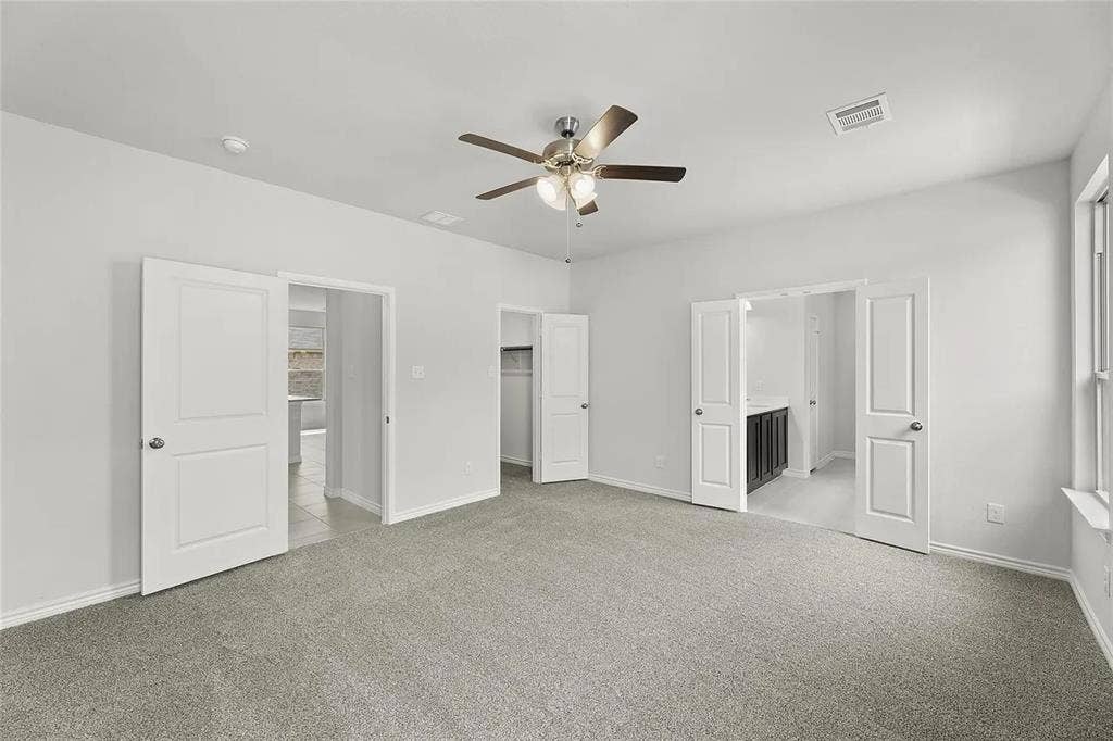 Neutral-toned carpeting, ceiling-mounted light fixture with fan, and multi-panel interior doors