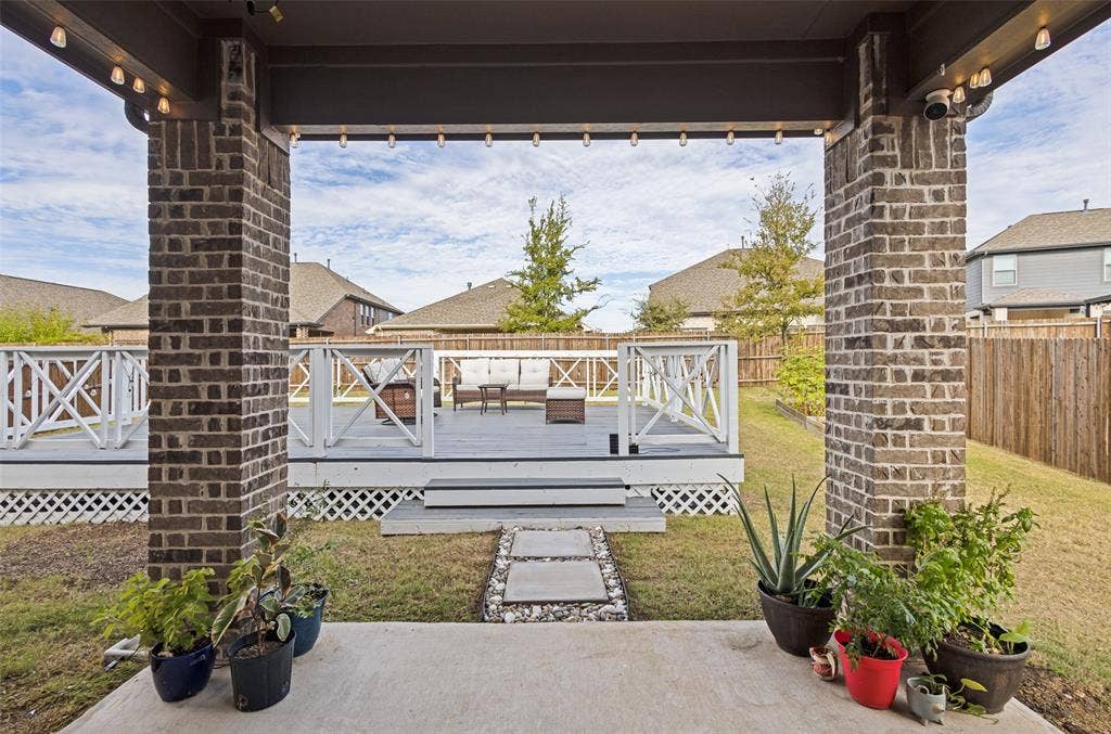 5313 Pratt Circle, McKinney, TX 75071 Covered patio featuring brick support columns, multi-level wood-finish decking, and white lattice railing
