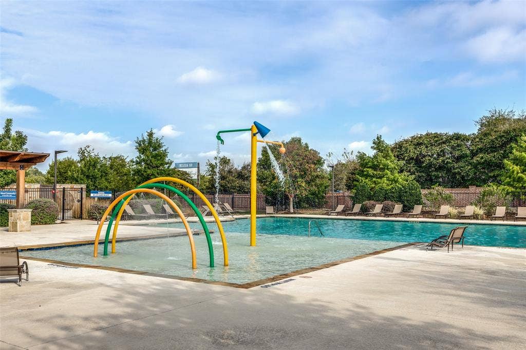 5313 Pratt Circle, McKinney, TX 75071 Swimming pool featuring a zero-entry area, water spray arches, overhead water feature, and expansive concrete decking