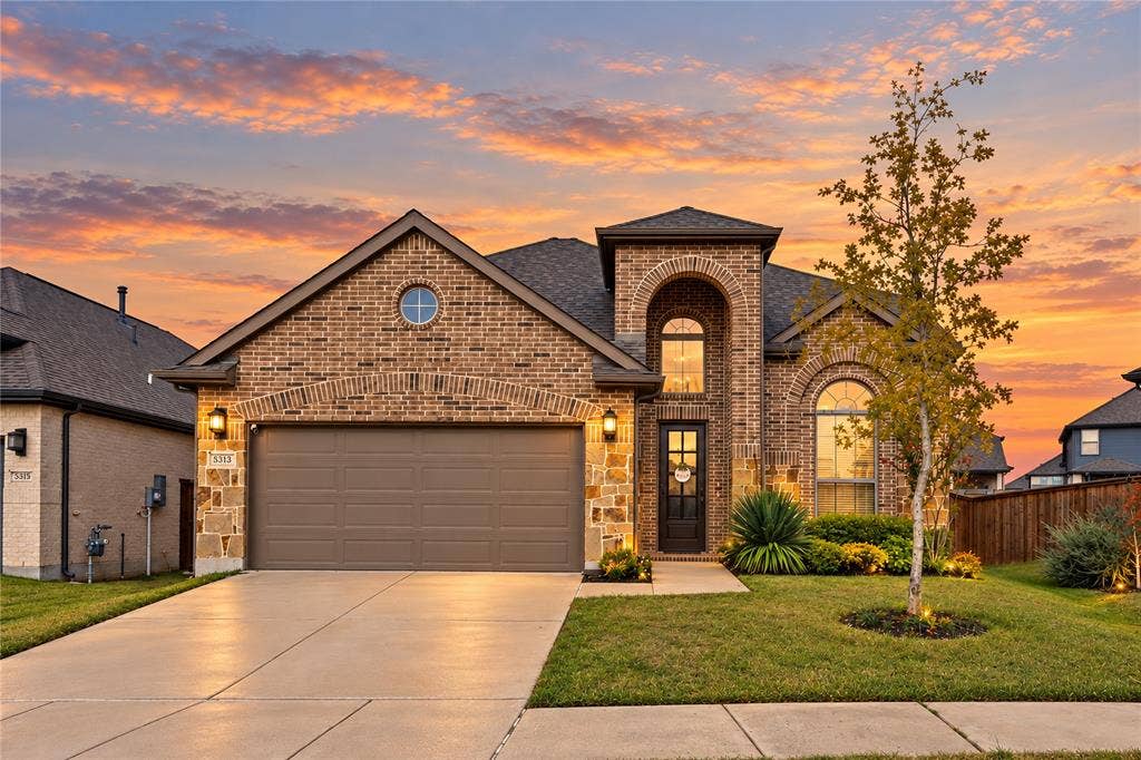 5313 Pratt Circle, McKinney, TX 75071 Brick exterior featuring an arched entryway, decorative stone masonry accents, a circular gable window, and a multi-car garage