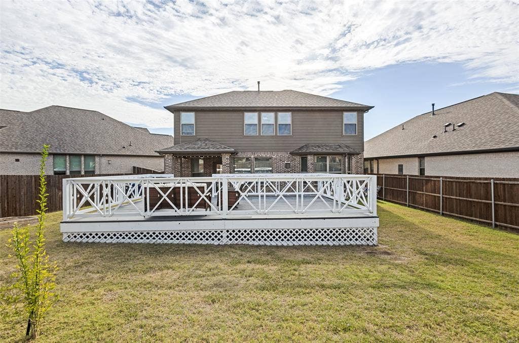 5313 Pratt Circle, McKinney, TX 75071 Raised wooden deck featuring decorative white X-pattern railing and white lattice skirting, complemented by a fenced backyard