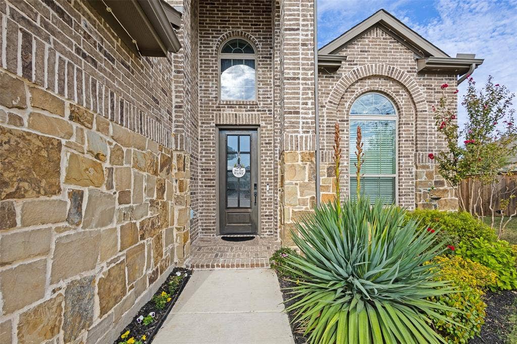 5313 Pratt Circle, McKinney, TX 75071 Exterior facade featuring multi-textured brick and stone masonry, arched window detailing, and a glass-paneled entry door