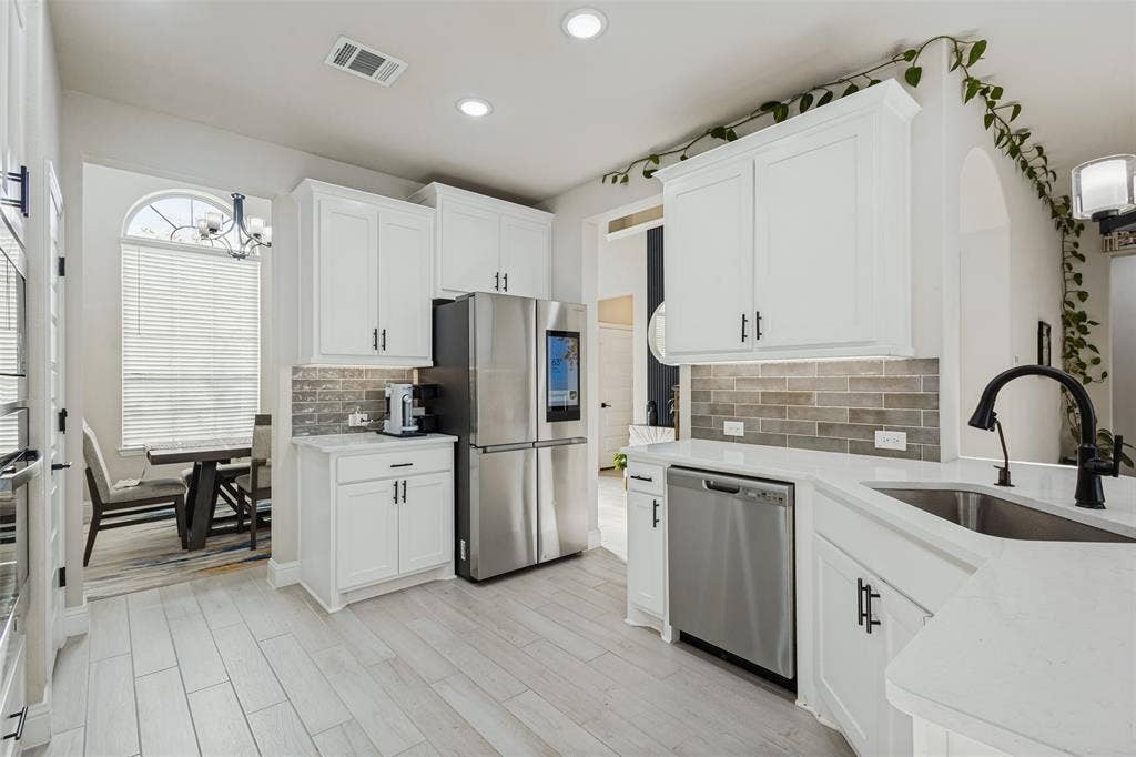 5313 Pratt Circle, McKinney, TX 75071 Kitchen featuring white cabinetry, light-toned stone-finish countertops, linear tile backsplash, stainless steel appliances, and wood-finish flooring