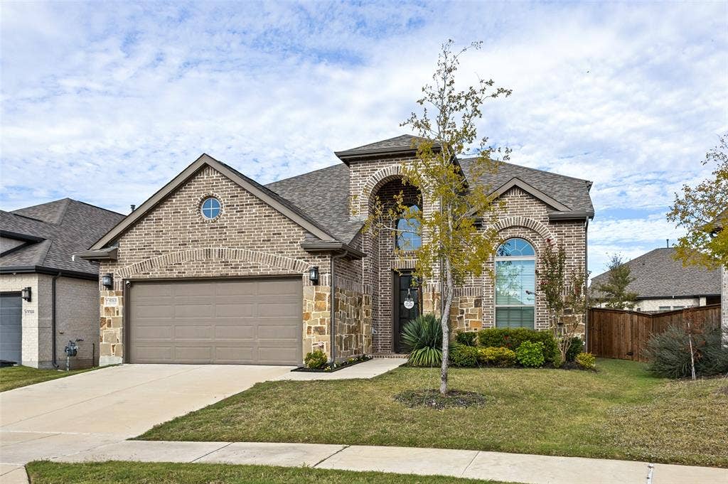 5313 Pratt Circle, McKinney, TX 75071 Multi-gable brick and stone exterior featuring an arched entryway, decorative oculus window, and attached two-car garage