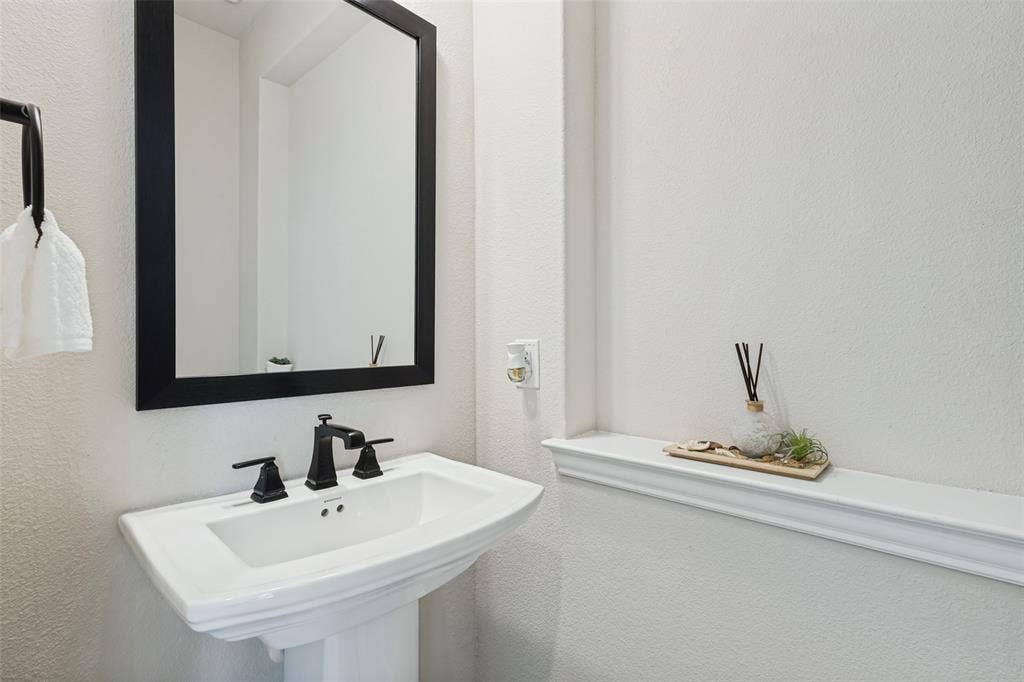 5313 Pratt Circle, McKinney, TX 75071 Pedestal sink featuring a wide basin and widespread matte black faucet, paired with a framed rectangular wall mirror