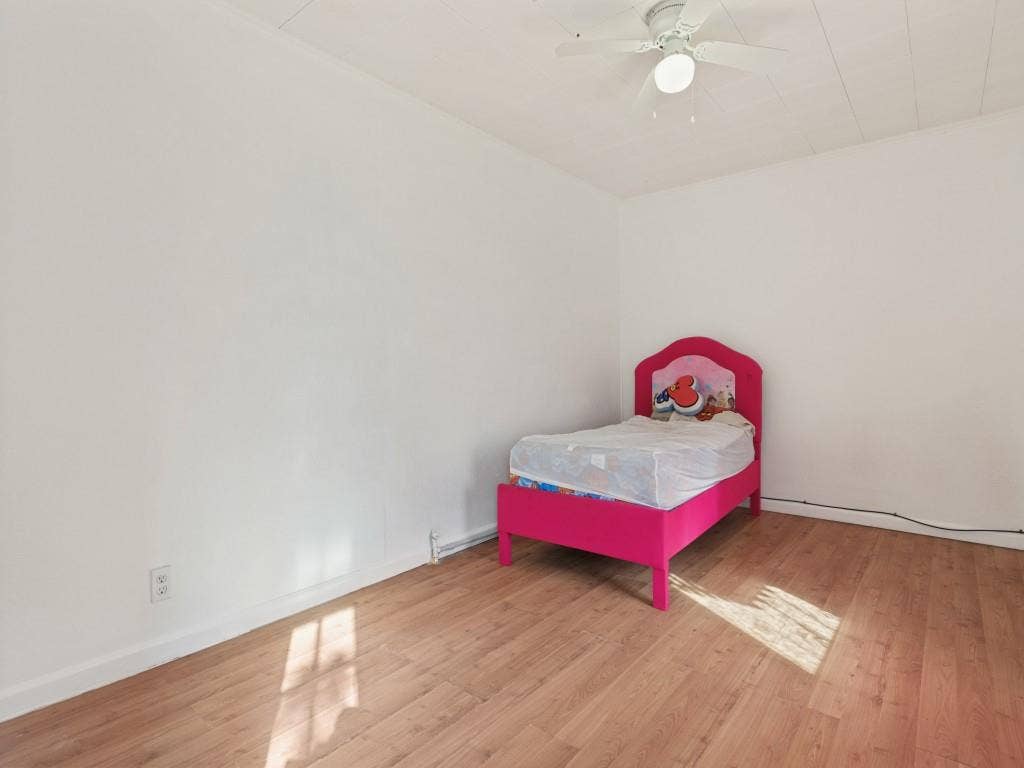 2009 Pecan Street, Commerce, TX 75428 Neutral interior space featuring wood-finish flooring, white walls, and a ceiling-mounted light fixture with integrated fan
