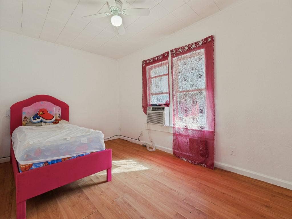 2009 Pecan Street, Commerce, TX 75428 Room featuring wood-finish flooring, a paneled ceiling with a central light fixture and fan, and dual windows