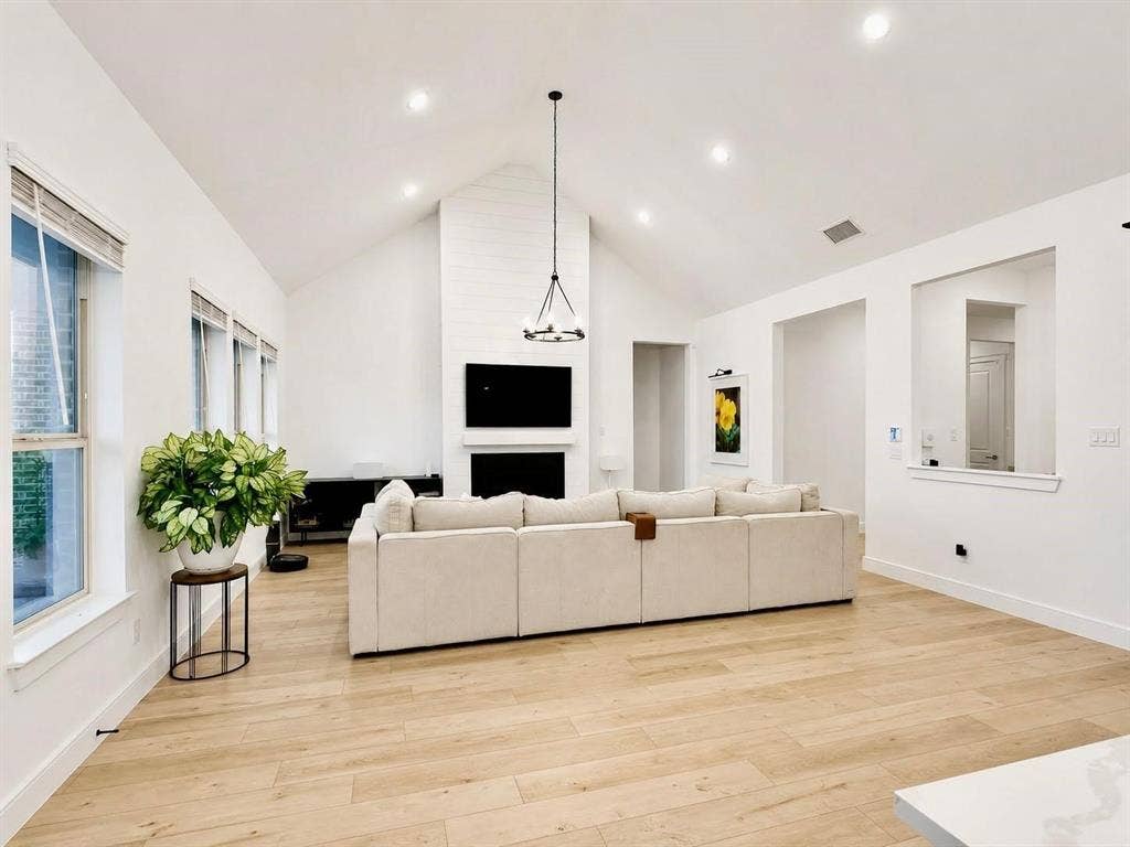 8912 Free Ferry Lane, McKinney, TX 75071 Vaulted ceilings, wood-finish flooring, recessed lighting, and a floor-to-ceiling fireplace with a prominent mantel
