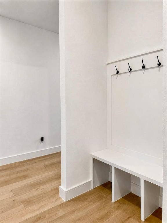 8912 Free Ferry Lane, McKinney, TX 75071 Built-in storage bench featuring white millwork, integrated coat hooks, and wood-finish flooring