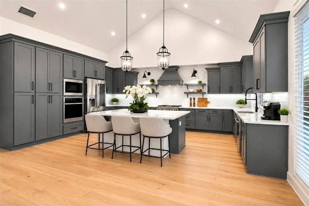 8912 Free Ferry Lane, McKinney, TX 75071 Kitchen featuring dark grey cabinetry, a central island with a stone-finish countertop, wood-finish flooring, a vaulted ceiling, and stainless steel built-in appliances