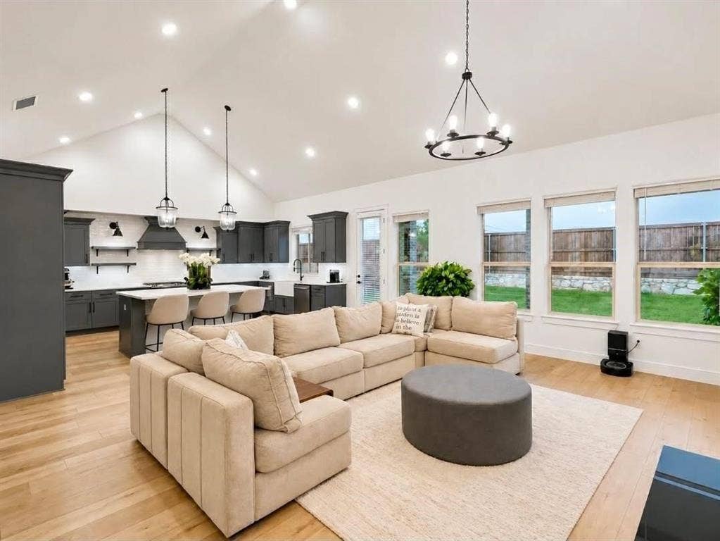 8912 Free Ferry Lane, McKinney, TX 75071 Vaulted ceilings with recessed lighting, wood-finish flooring, kitchen island with breakfast bar, dark-toned cabinetry, and a tiered chandelier