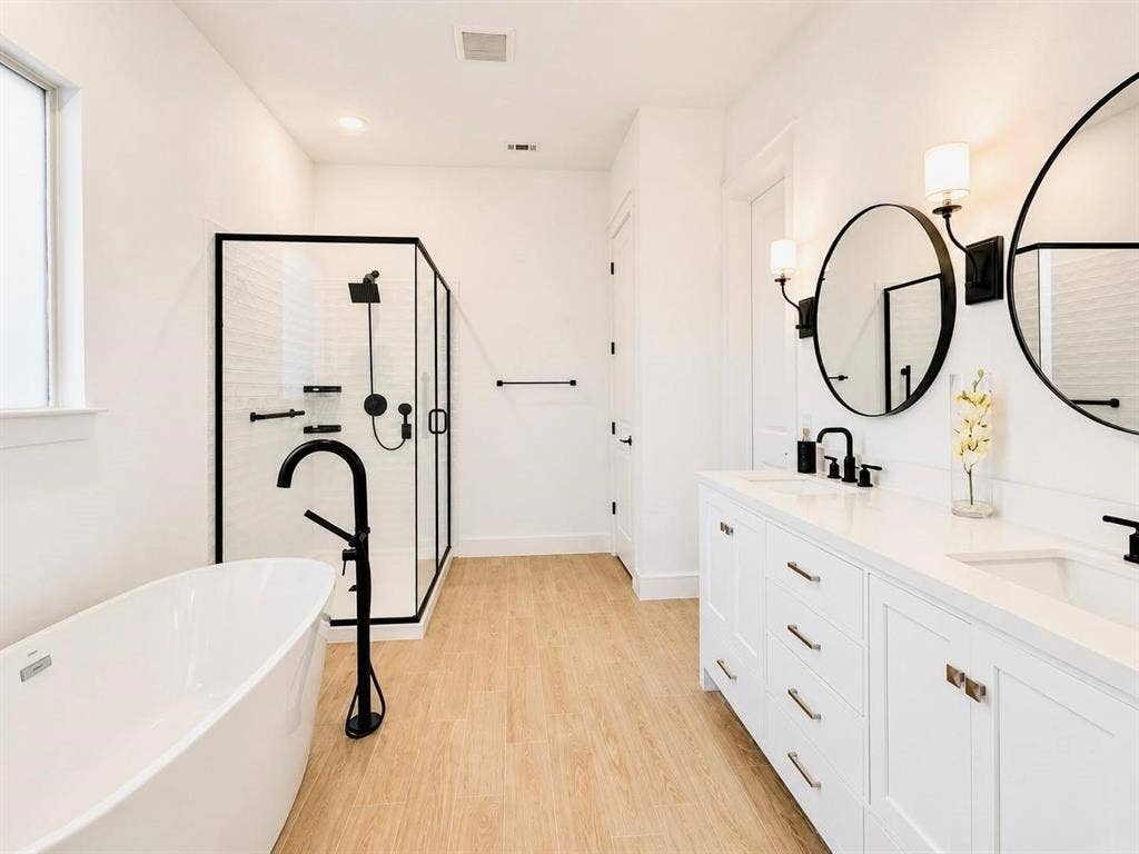 8912 Free Ferry Lane, McKinney, TX 75071 Dual-vanity cabinet with quartz countertop, undermount sinks, and matte black fixtures, paired with a freestanding soaking tub, walk-in glass shower, and wood-finish flooring