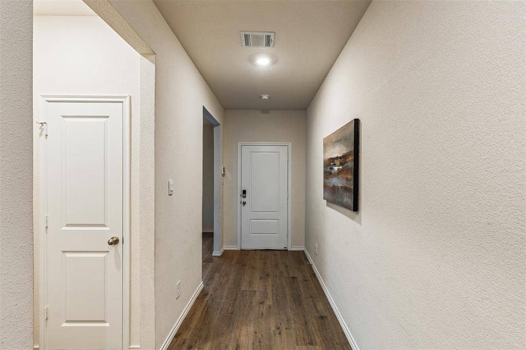 Neutral-toned interior featuring wood-finish flooring, a multi-panel entry door with electronic deadbolt, and recessed ceiling lighting
