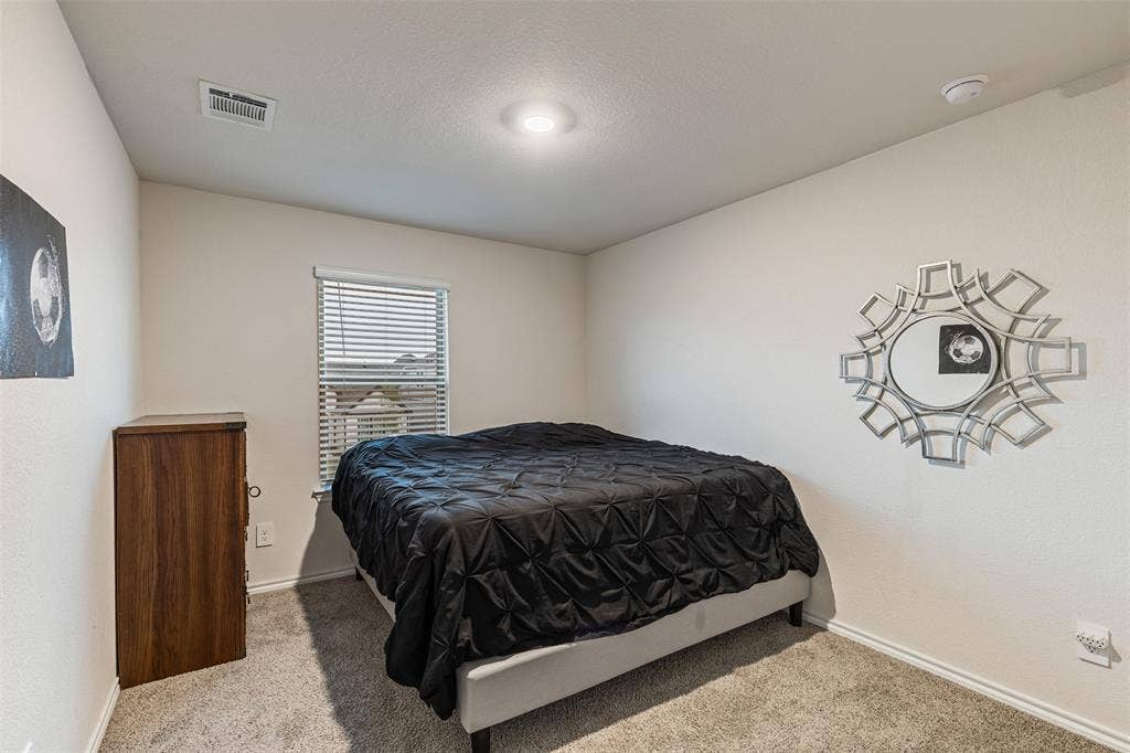 Neutral-toned interior space featuring wall-to-wall carpeting, a window with horizontal blinds, and recessed ceiling lighting