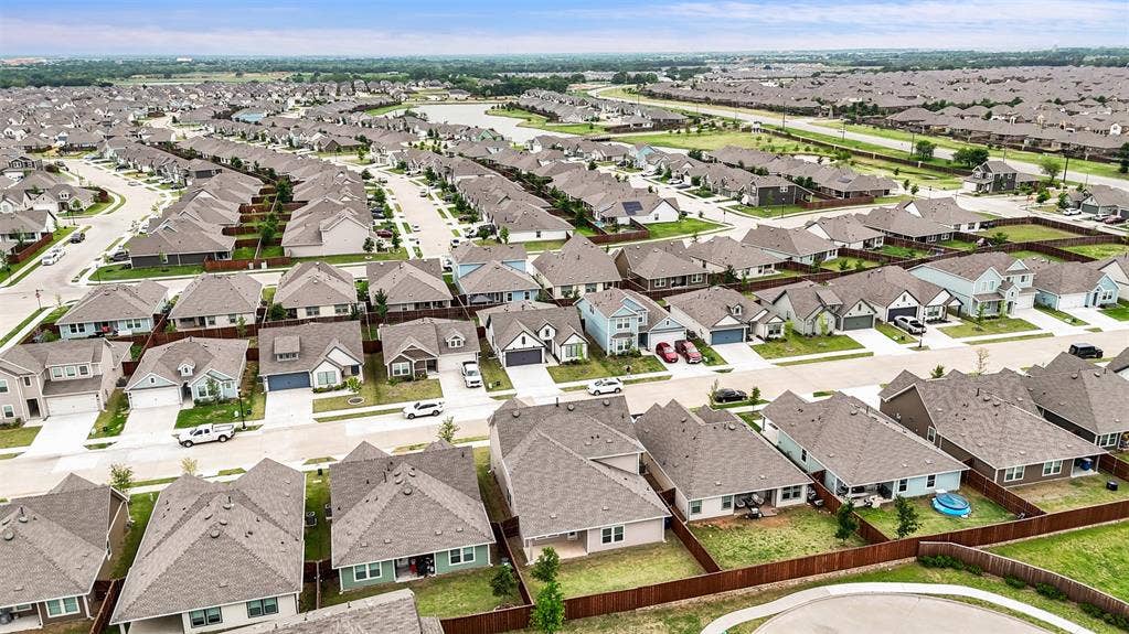 Aerial perspective of a planned residential community featuring paved street networks, uniform roofing materials, and fenced lot perimeters