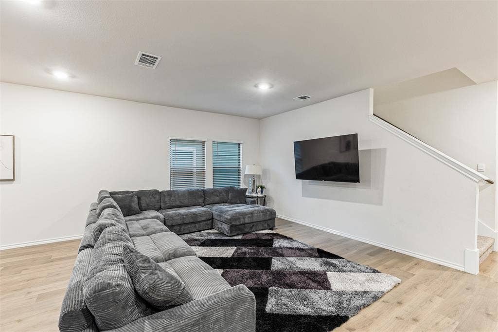 Neutral interior space featuring wood-finish flooring, recessed lighting, and a staircase with a wooden handrail