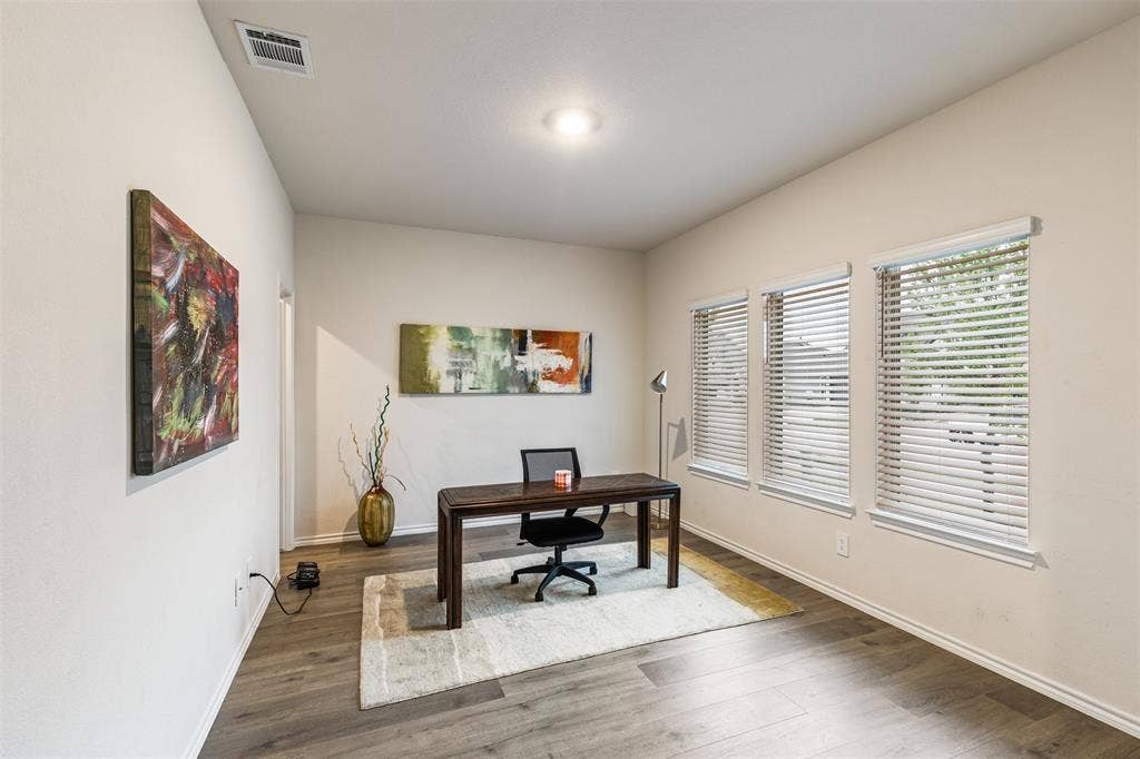 Wood-finish flooring, neutral wall tones, and triple windows with horizontal blinds