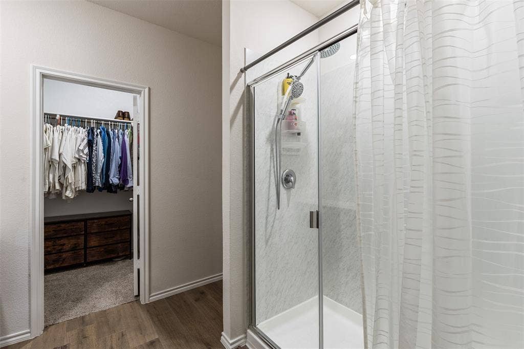 Walk-in shower with a sliding glass door, surround tile, and a handheld showerhead