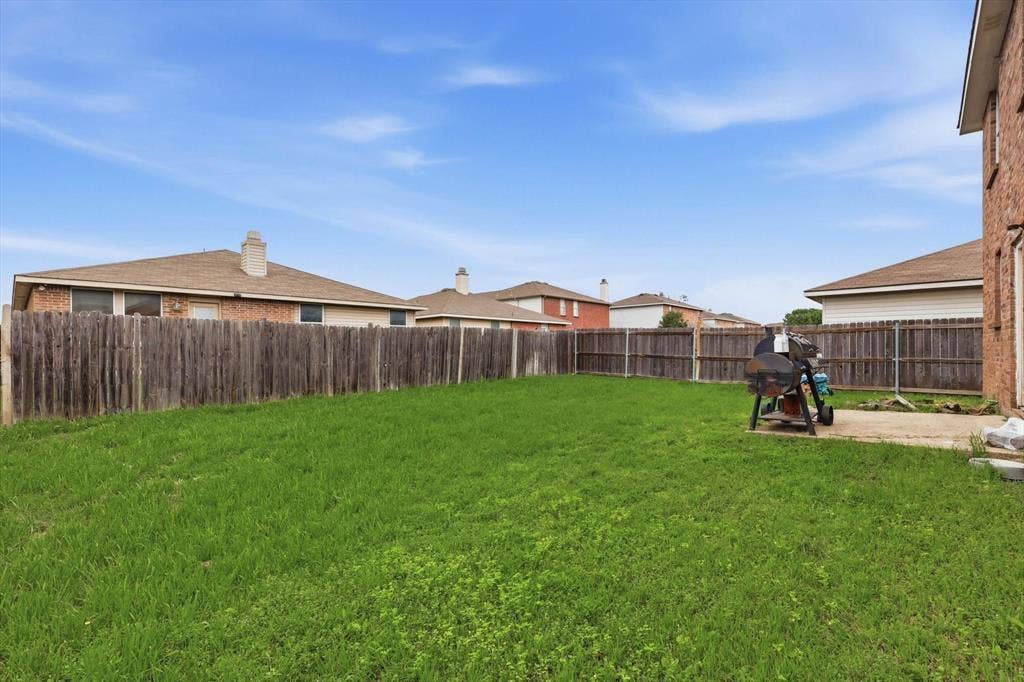 1633 Sierra Meadow Lane, Fort Worth, TX 76247 Rear yard featuring an open grass lawn, concrete patio, and a perimeter wood privacy fence