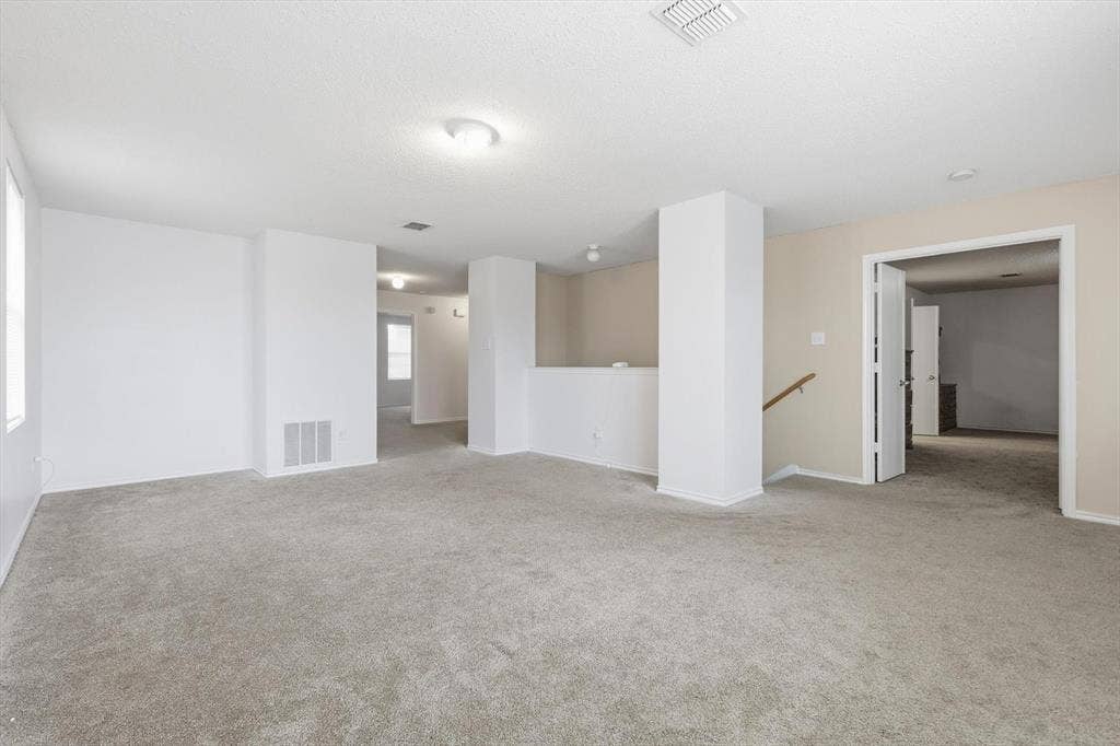 1633 Sierra Meadow Lane, Fort Worth, TX 76247 Expansive interior space featuring neutral wall tones, wall-to-wall carpeting, flush-mount lighting fixtures, and a structural column