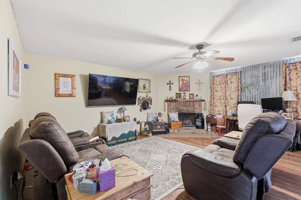 1633 Sierra Meadow Lane, Fort Worth, TX 76247 Brick fireplace with wooden mantel, wood-finish flooring, and ceiling fan with light fixture