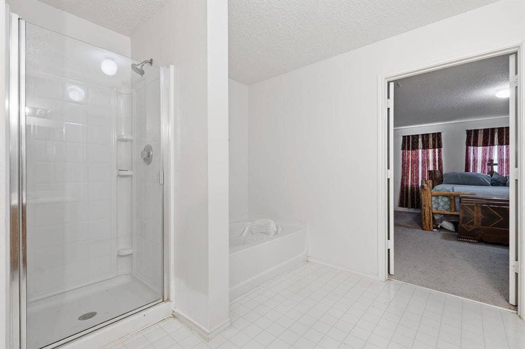 1633 Sierra Meadow Lane, Fort Worth, TX 76247 Bathroom featuring a glass-enclosed shower, a deep soaking tub, and tile flooring