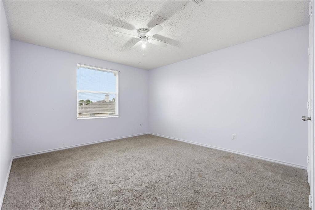 1633 Sierra Meadow Lane, Fort Worth, TX 76247 Neutral-toned interior space featuring wall-to-wall carpeting, a single window, and a white ceiling fan with integrated lighting