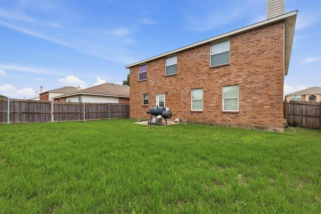 1633 Sierra Meadow Lane, Fort Worth, TX 76247 Exterior brick facade featuring a grass lawn, privacy fencing, and a concrete patio