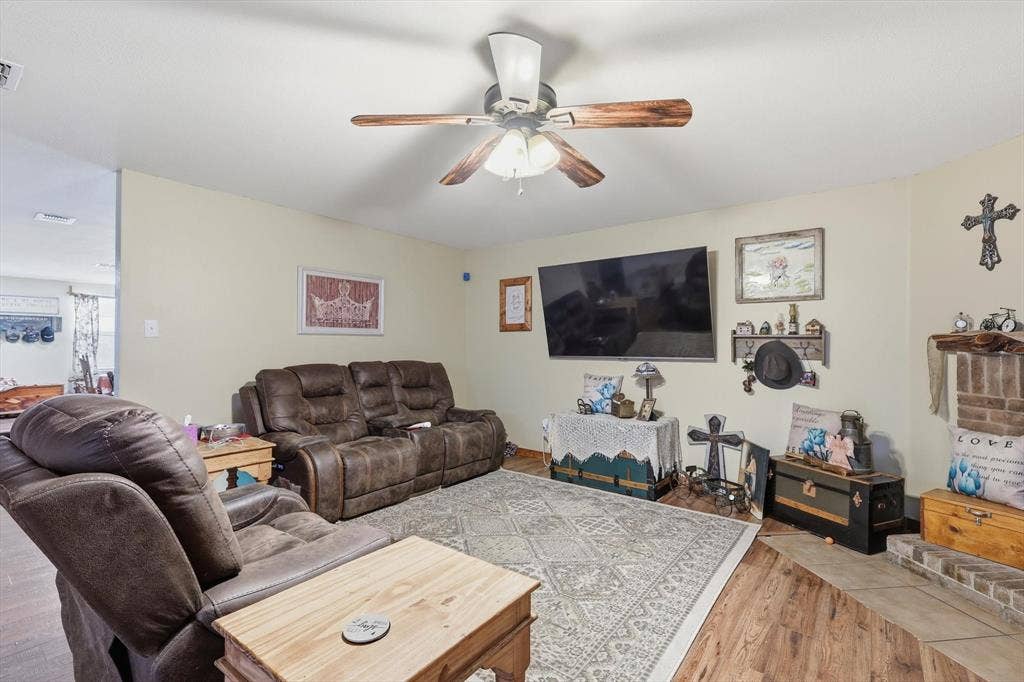 1633 Sierra Meadow Lane, Fort Worth, TX 76247 Living area featuring wood-finish flooring, a ceiling fan with integrated lighting, and a brick fireplace hearth