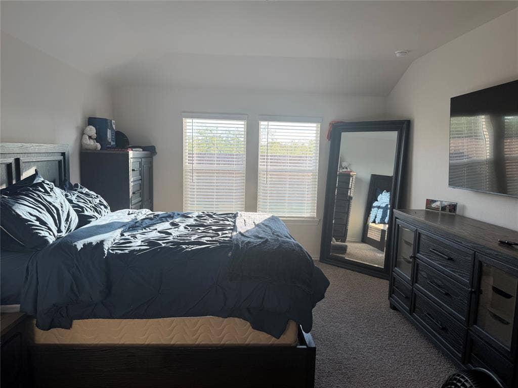 Bedroom featuring neutral wall paint, high ceilings, carpeting, and two windows with horizontal blinds