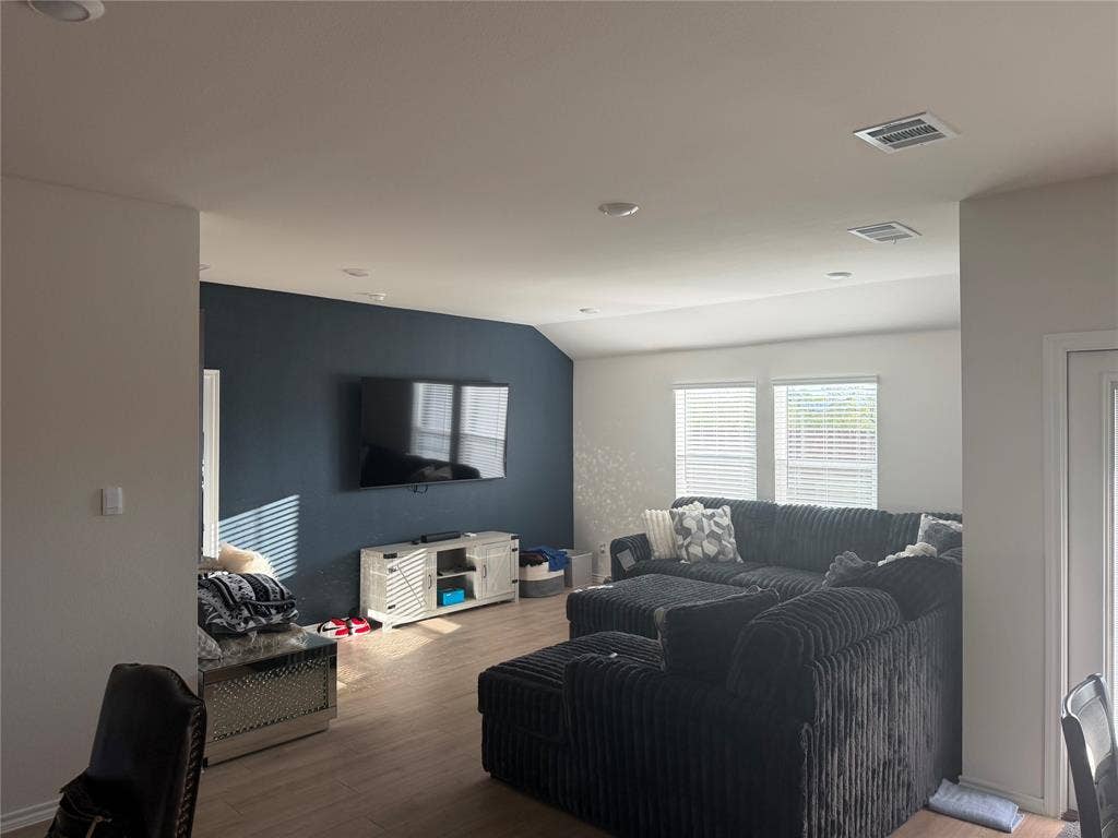 Living area featuring wood-finish flooring, recessed lighting, and a prominent dark accent wall