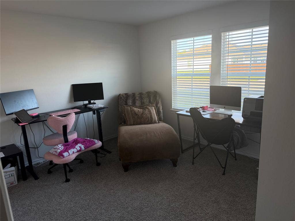 Neutral-toned room featuring neutral carpeting and two windows with horizontal blinds