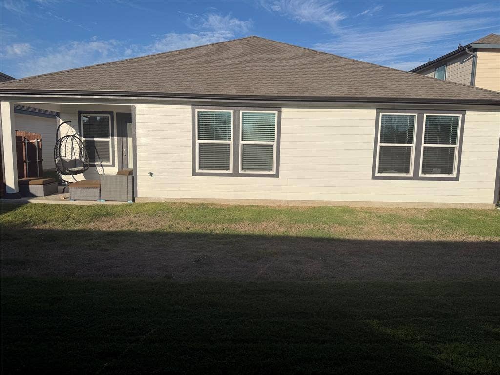 Exterior rear elevation featuring horizontal siding, a covered patio with concrete flooring, and a hip roof
