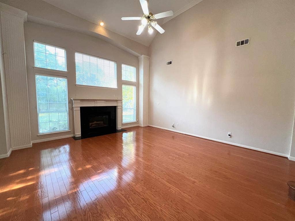 Vaulted ceilings, wood-finish flooring, fireplace with a mantel, and oversized windows