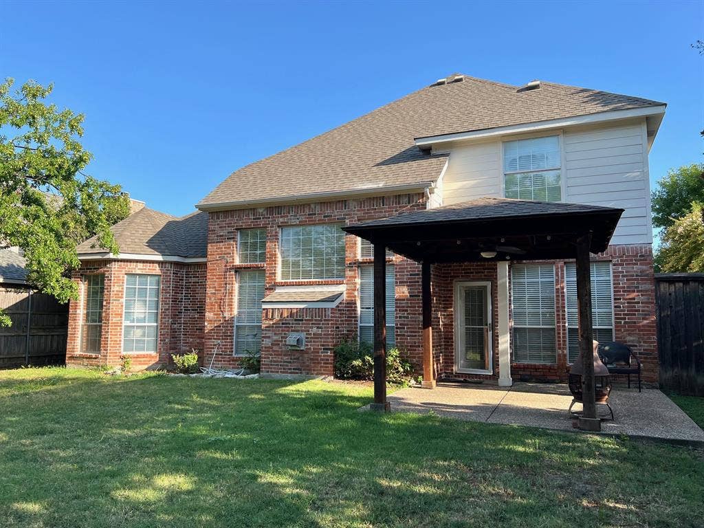 Brick exterior residence featuring a covered patio, pergola, concrete hardscaping, and multi-pane windows