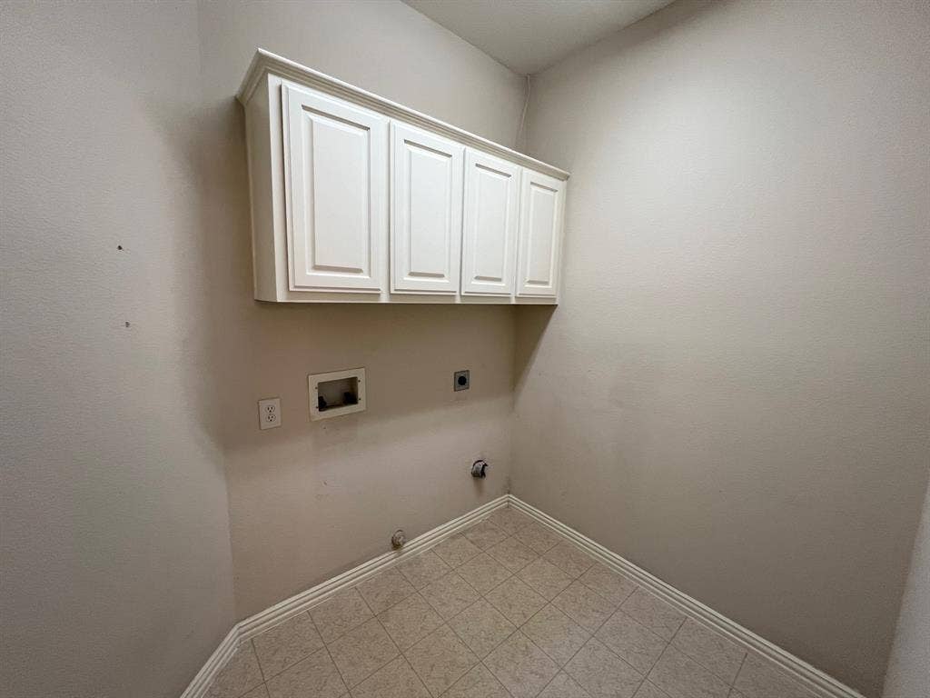 Wall-mounted white cabinetry with recessed-panel doors and neutral tile flooring