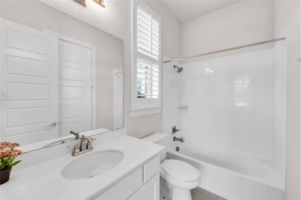 2971 Gaulding Drive, Prosper, TX 75078 Bathroom featuring white vanity cabinetry, integrated sink, polished chrome faucet, white subway tile shower surround, and louvered shutters